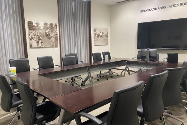 Boardroom with tables and chairs in front of a TV monitor