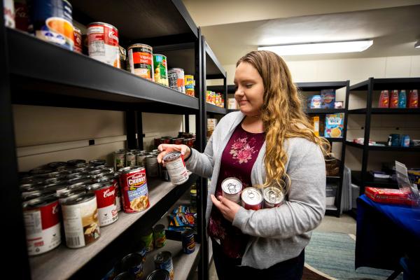 Student grabs canned goods from the Big Blue Pantry shelves.