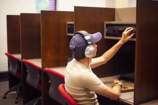 Student uses headphones and other equipment at the Fine Arts Library Media Center.