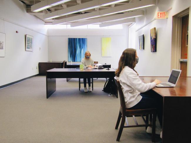 Two students study at separate tables at the Fine Arts Library.
