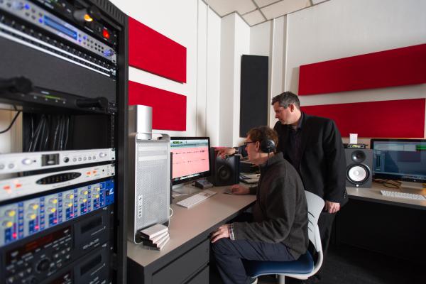 View of two men in front of a computer screen and sound editing equipment in the Louie B. Nunn Center.