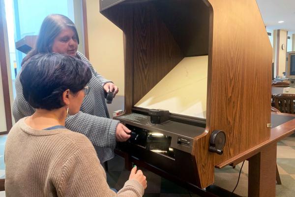 A librarian demonstrates how to use a microform reader at Young Library.
