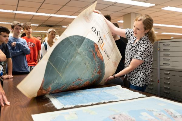 Librarian shows maps to a class in the Science & Engineering Library.
