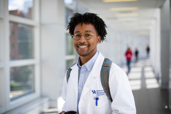 Student from College of Medicine in white coat with backpack.