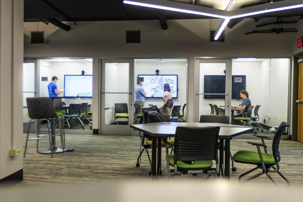 Students study in collaboration rooms in the Stacks