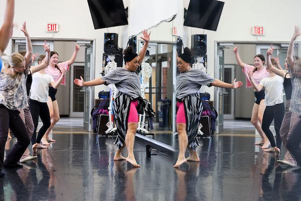 A group of dancers face their reflections in a mirror