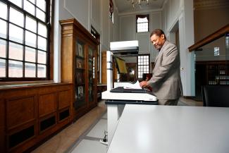 A man smiles as he uses a book scanner