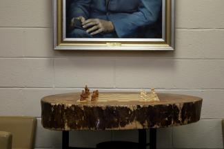 A chess board set in an oak stump beneath a portrait