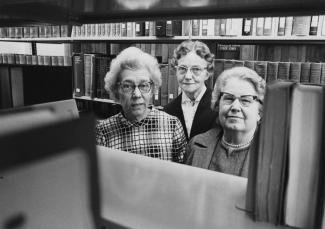 Three women seen through the stacks of the library archives