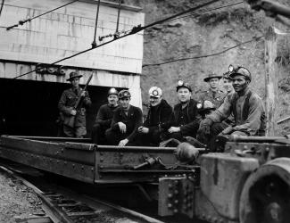 Striking miners leave a mine shaft in a cart guarded by police