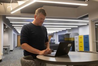 A librarian works on his laptop in the Stacks