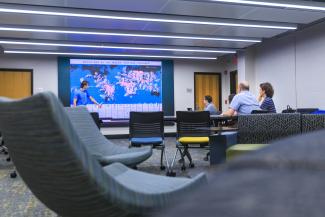 A student gives a presentation using a visualization wall