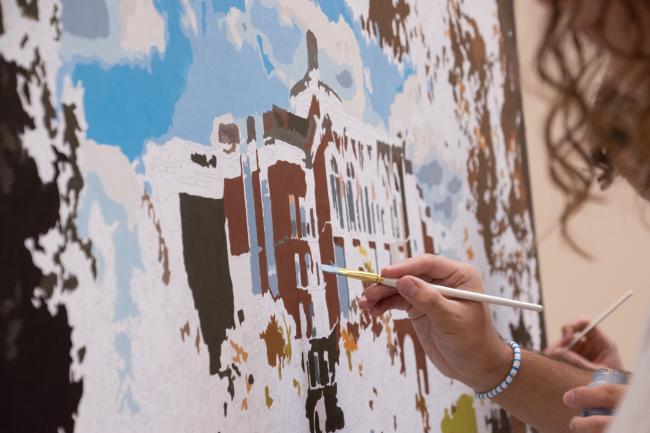 Close up of a brush painting a mural of William T Young Library
