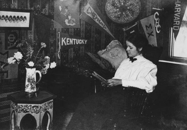A student reads in her dorm room under banners adorning the walls
