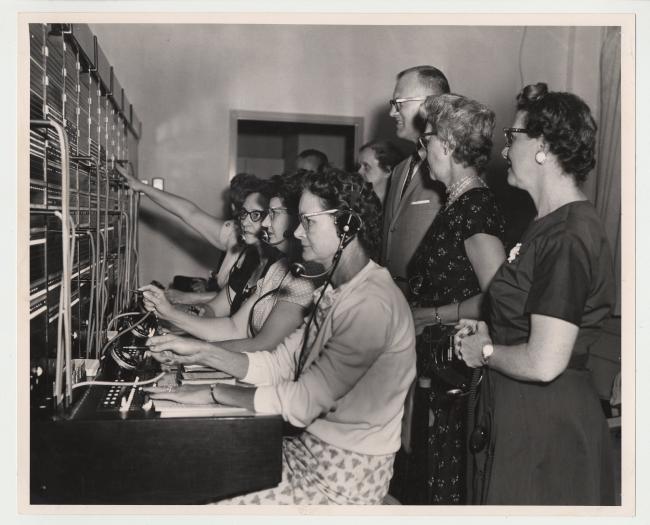 Unidentified men and women operate a switchboard in an archival photograph
