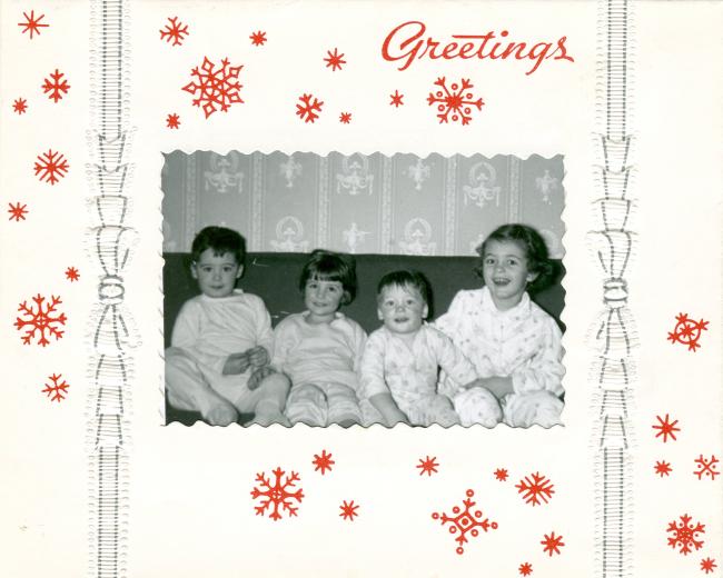 A Christmas card with red snowflakes and a picture of four young children on a couch
