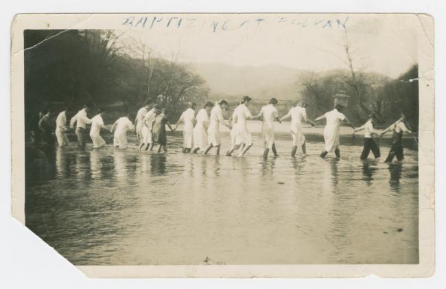 Archival photograph depicting a chain of women wearing white in the Cumberland River during a baptism