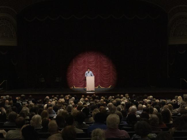 Percival Everett behind a podium on a stage in front of a large crowd