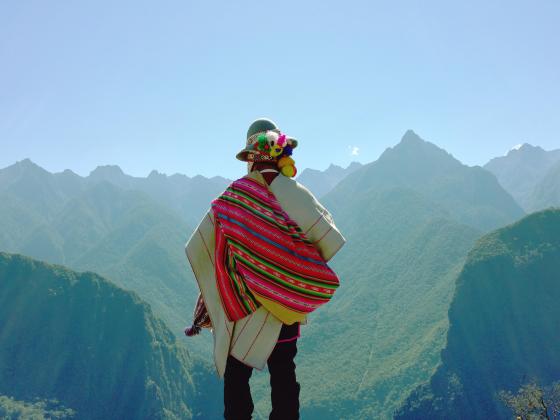 A person in colorful dress overlooks a mountain valley