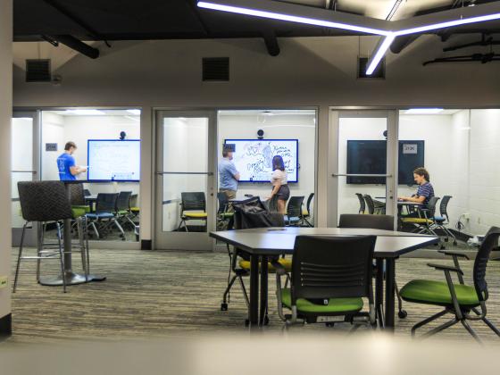 Students study in collaboration rooms in the Stacks