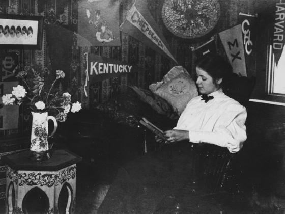 A student reads in her dorm room under banners adorning the walls