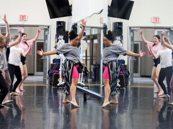 A group of dancers face their reflections in a mirror