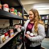 Student grabs canned goods from the Big Blue Pantry shelves.