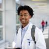 Student from College of Medicine in white coat with backpack.